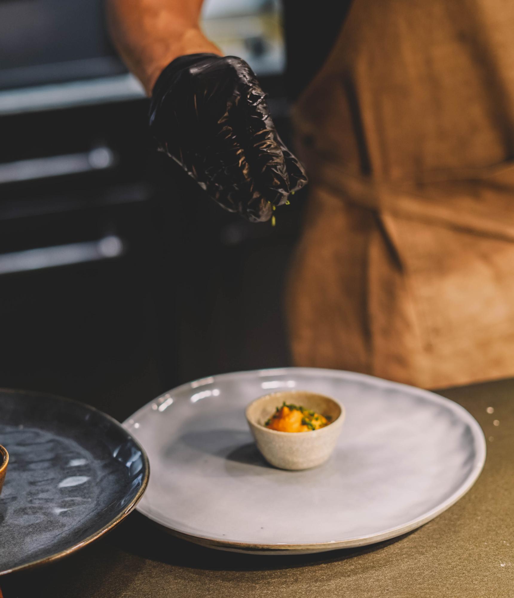 Chef refining a plated dish in a studio kitchen